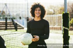 Athletic man holding soccer ball and smiling while at practice bYdn64