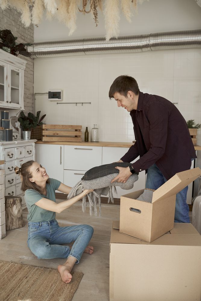 Cheerful couple unpacking boxes in light kitchen