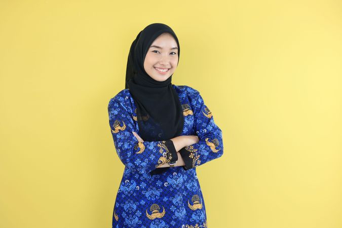 Woman in Hijab and Korpri Batik Blue Uniform Showing Confident Gesture by Folding Her Arms.
