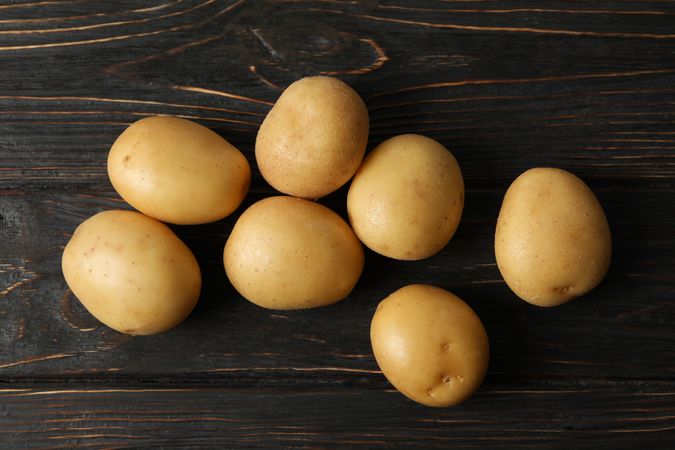 Top view of potatoes scattered on dark wooden table