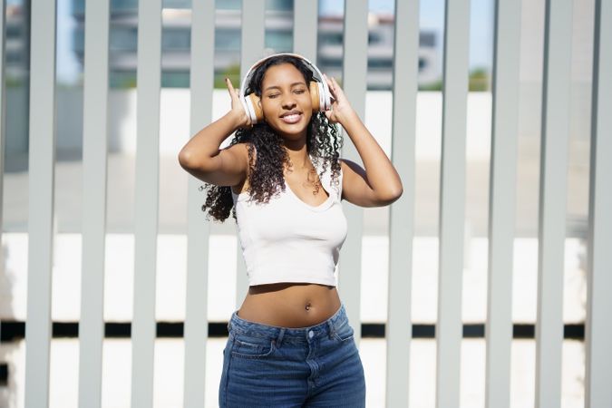 A Young Woman is Joyfully Enjoying Music while in a Vibrant Urban Setting outdoors