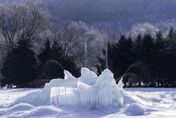 An ice fountain in the snow surrounded by trees