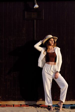 A long hair fashion model with a hat at the beach with a dark background