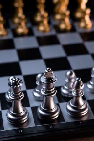 Silver chess pieces on checkered board, portrait view
