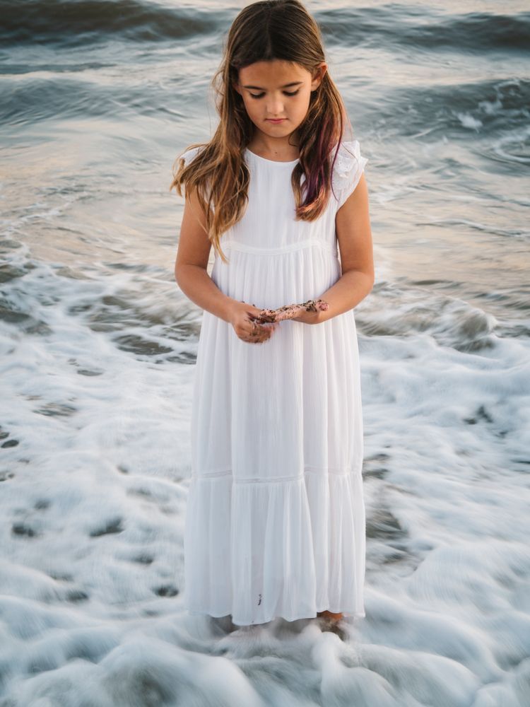 Smiling girl standing on seaside among waves