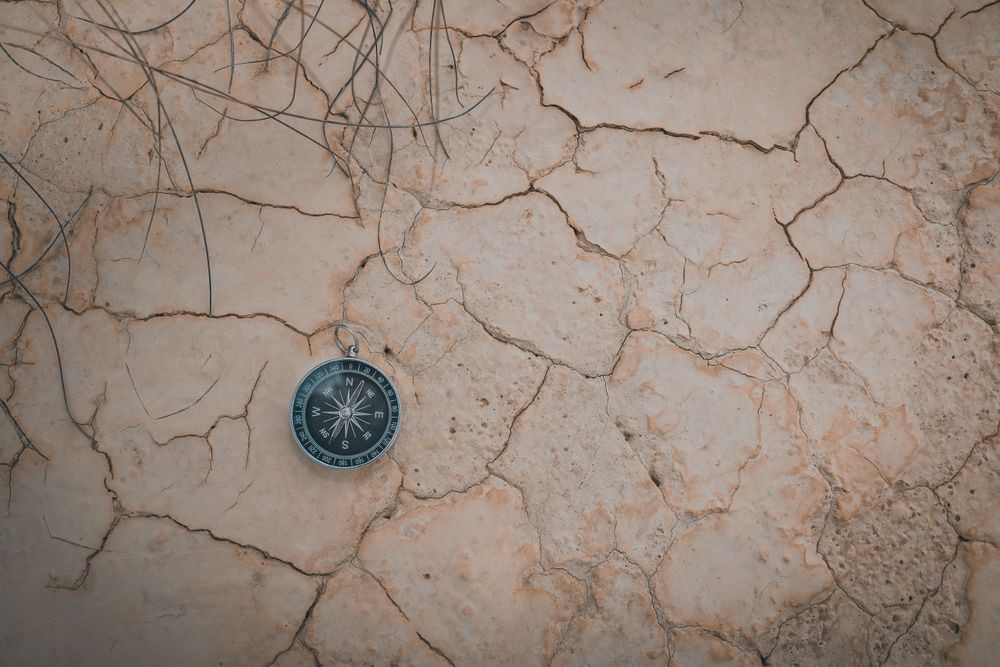 Big compass on dry cracked desert area