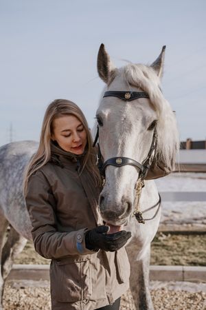 Warm dressed woman with gray horse outside