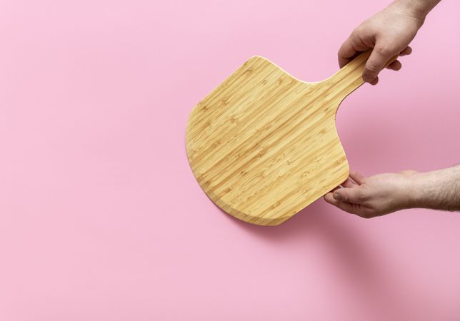 Empty pizza board on a pink background