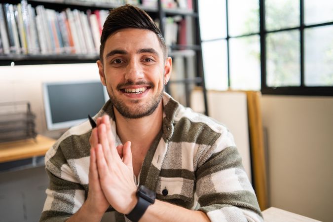 Male creative smiling with hands together in thank you sign in relaxed modern office