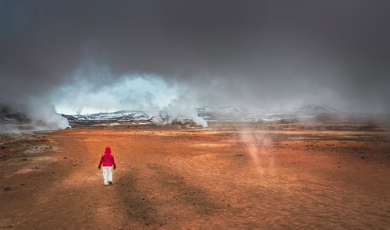 Traveler walking in valley near geysers
