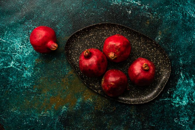 Whole pomegranates on dark ceramic plate