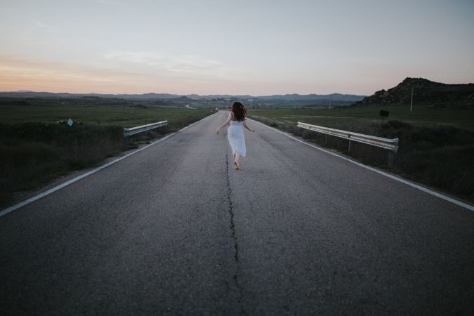 Anonymous woman running along countryside road