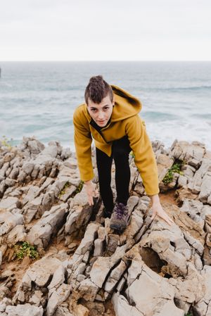 Woman in yellow hoodie on stony shore