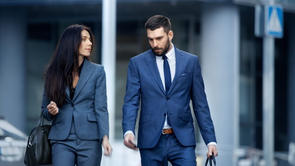 Business Woman and Business Man in Tailored Suits Walk on the Busy Big City Street.