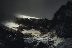 Harsh mountain snowy peak shrouded in fog