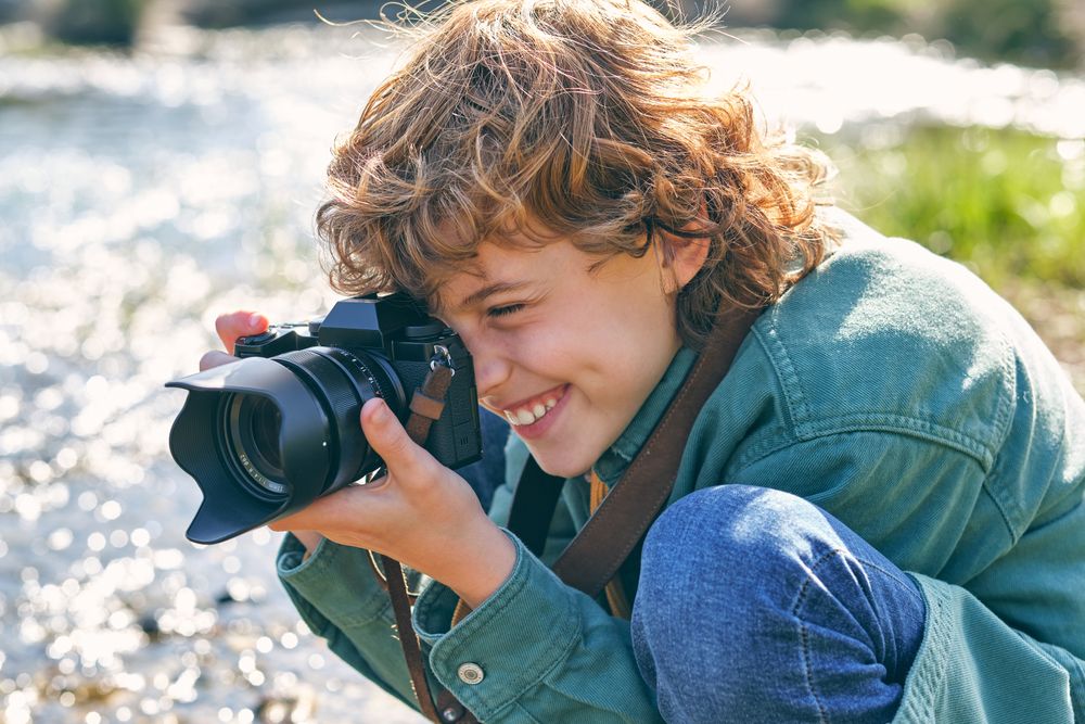 Smiling boy taking photo of nature on shore
