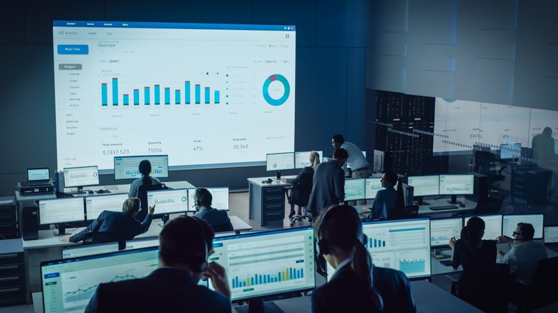 Analysts Monitor Data in High-tech Control Room. Large Screen Displays Analytics Dashboard With Charts.