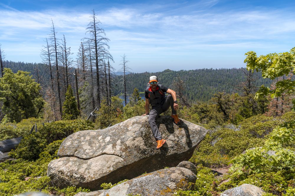 Relaxed hiker resting on big rock in forest
