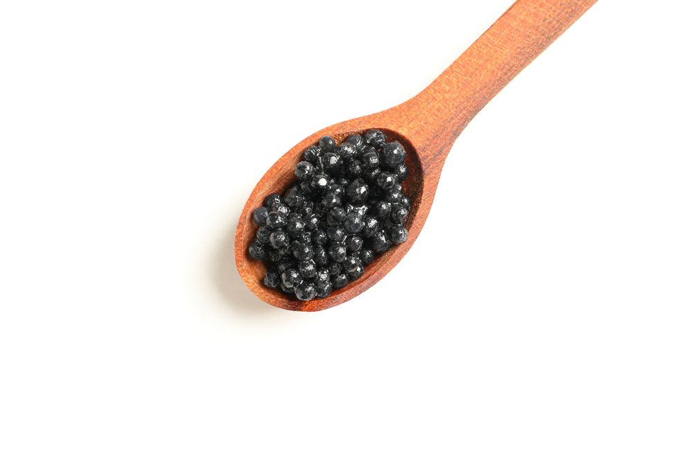 Spoon with caviar isolated on plain background, top view