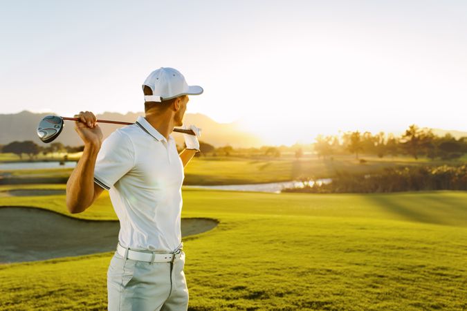 Athletic male holding golf club and looking away