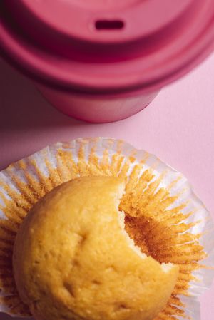 Bitten breakfast muffin on pink background