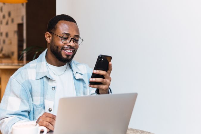 Cheerful Black man browsing smartphone in cafe