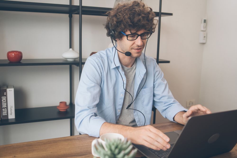 Male telemarketing with head set talking to customer while working at home