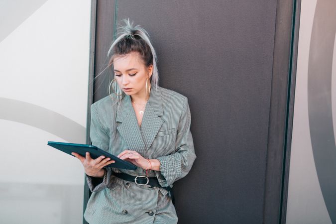 Stylish businesswoman with laptop leaning on wall