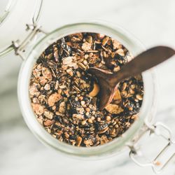 Top view glass container of homemade granola, close up, square crop