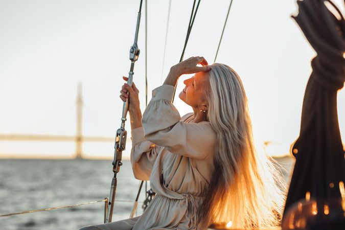 Relaxed older woman sweeping her hair back on a boat