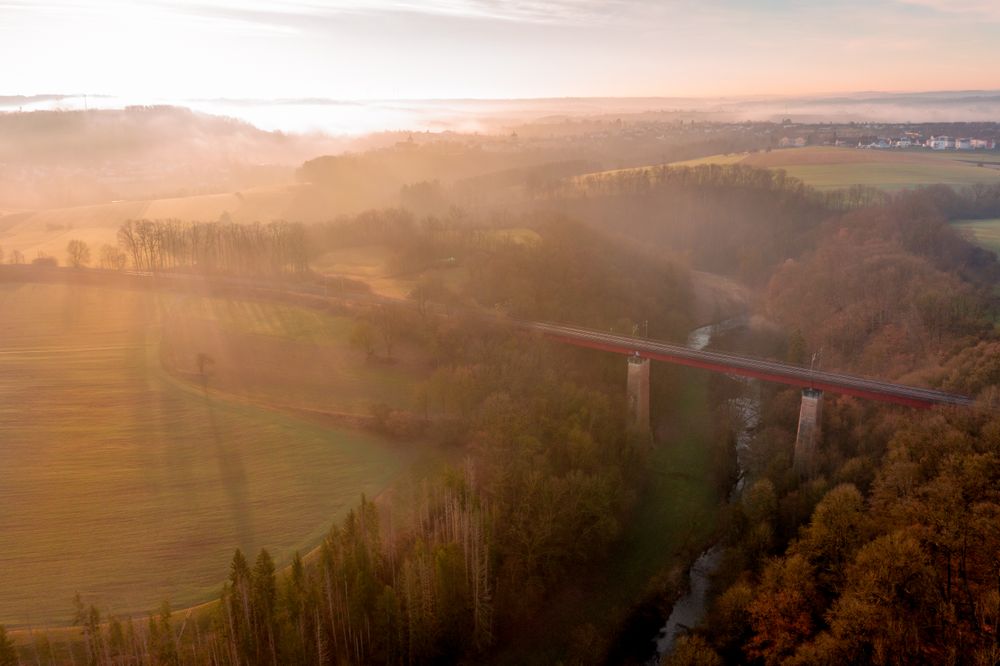 Drone aerial view of a railway bridge crossing the river in nature at sunrise on a winter morning