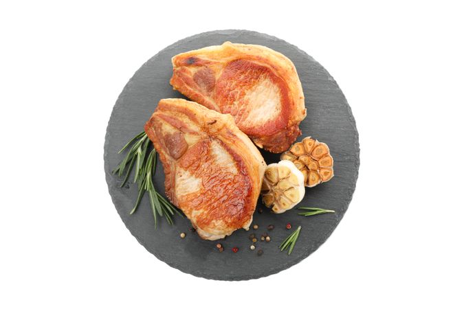Tray with fried pork steaks isolated on light background. Grilled food