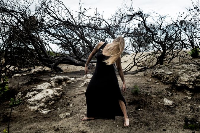 Woman posing on ground near dry trees