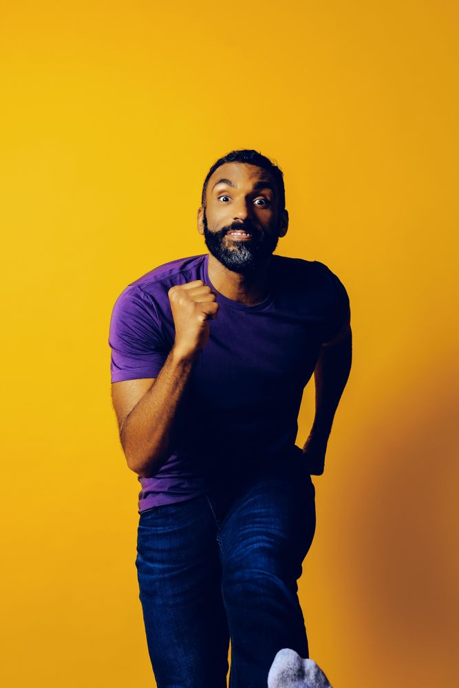 Black man in running position in yellow studio