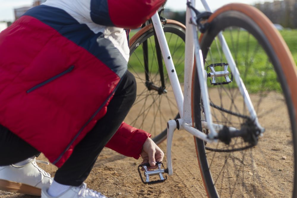 Man repairing his bicycle outdoors on park trail