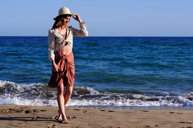 A fashion model with a hat at the beach before sunset