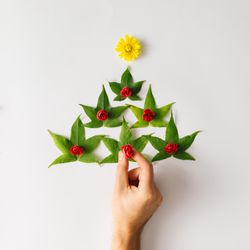 Christmas tree made of leaves and flowers with hand