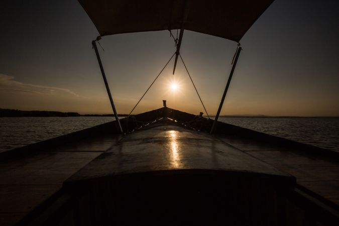 Front of boat riding along sea at twilight