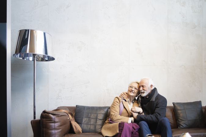 Older couple embracing on sofa looking up