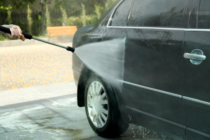 A man washes a car in a manual car wash. Clear car