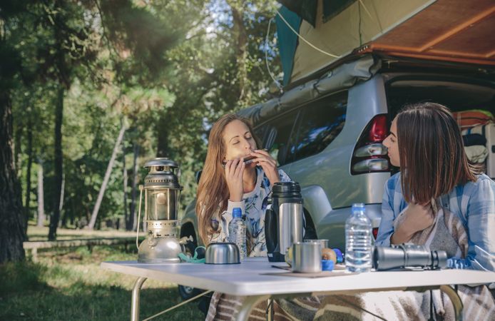Woman playing harmonica with friend while camping