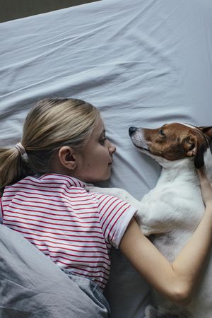 Top view of girl laying with dog in bed