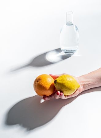 Composition of a hand with citrus and jar of water