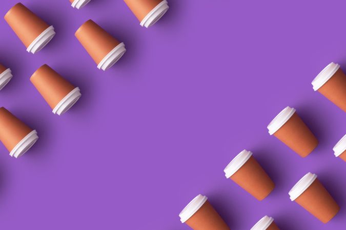 Disposable coffee cups in the corners on purple background