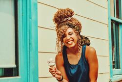 Amused Black female snacking on an ice cream cone in the sun