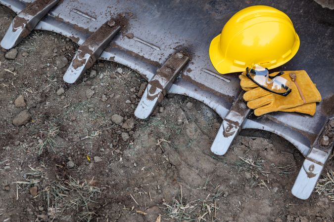 Hardhat, Gloves and Protective Glasses Resting on Bulldozer Bucket Abstract