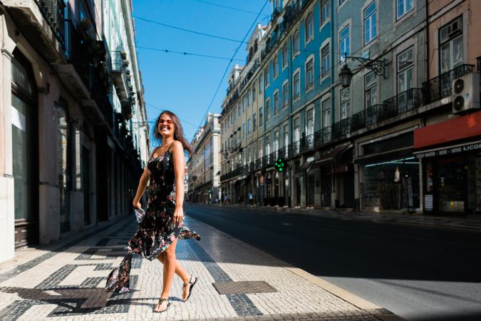 Carefree woman in sundress spinning on street