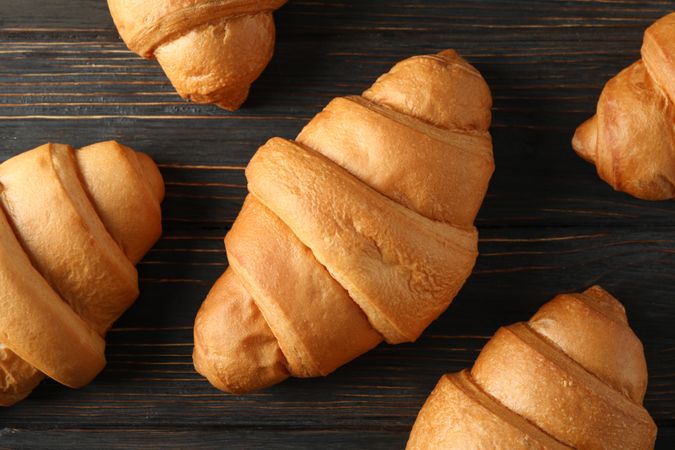 Tasty croissants arranged on wooden background, top view