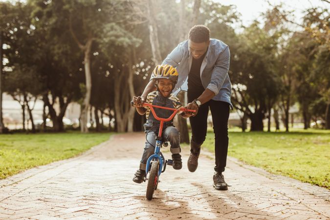 Boy learning to ride a bicycle with his father in park