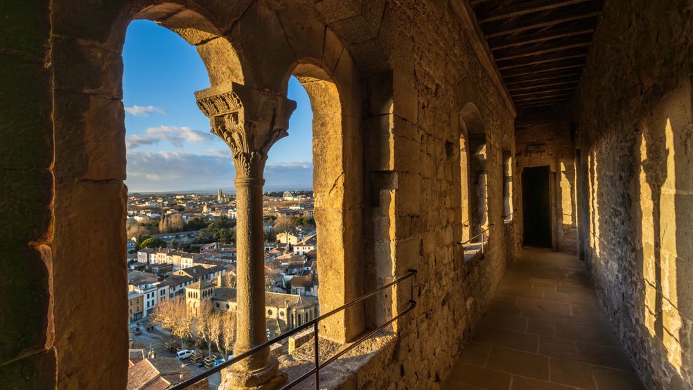 Gallery overlooking the city of Carcassonne. A long hallway with arched windows and a view of the city below